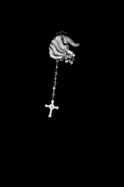 A black and white image of a rosary, showcasing its intricate beads and cross against a soft, blurred background